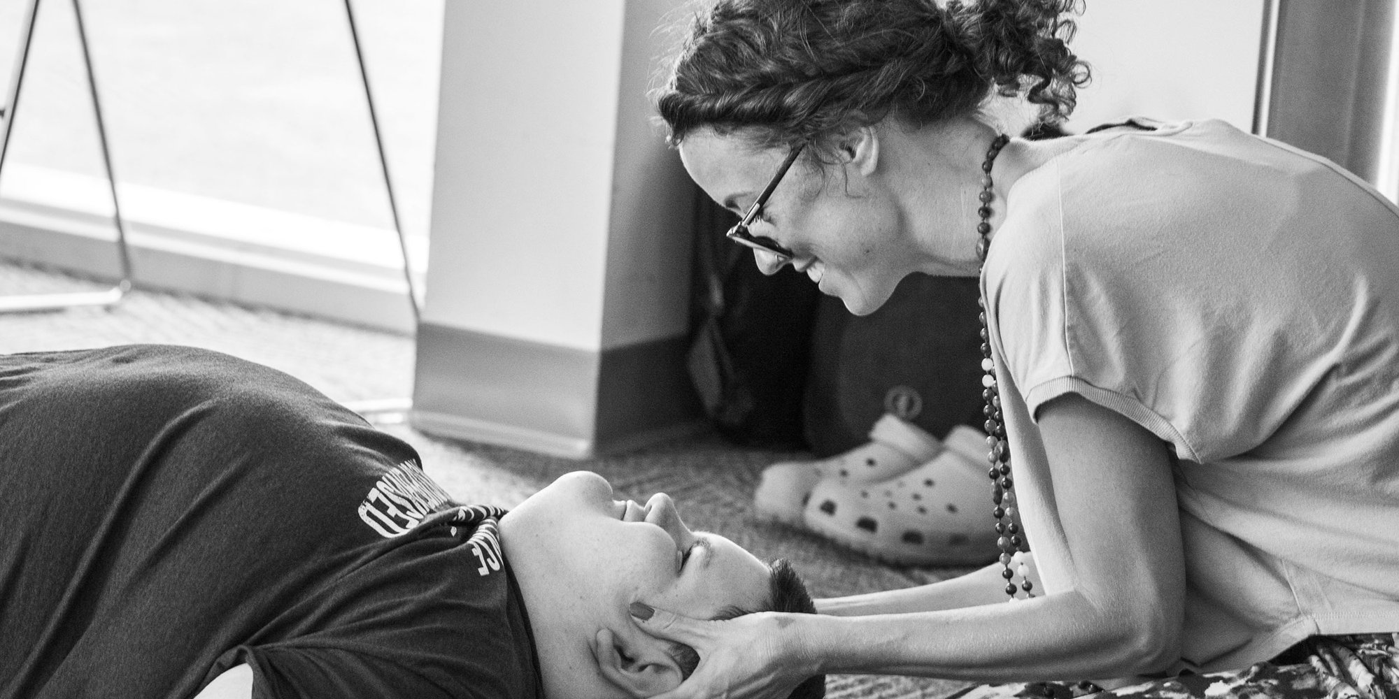 Sam kneeling beside a participant lying on a mat, gently supporting their head